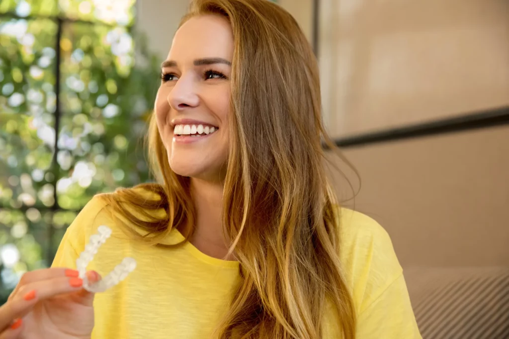 woman smiling holding her Invisalign