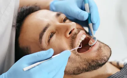 A man sat in a dentists chair getting a check up.